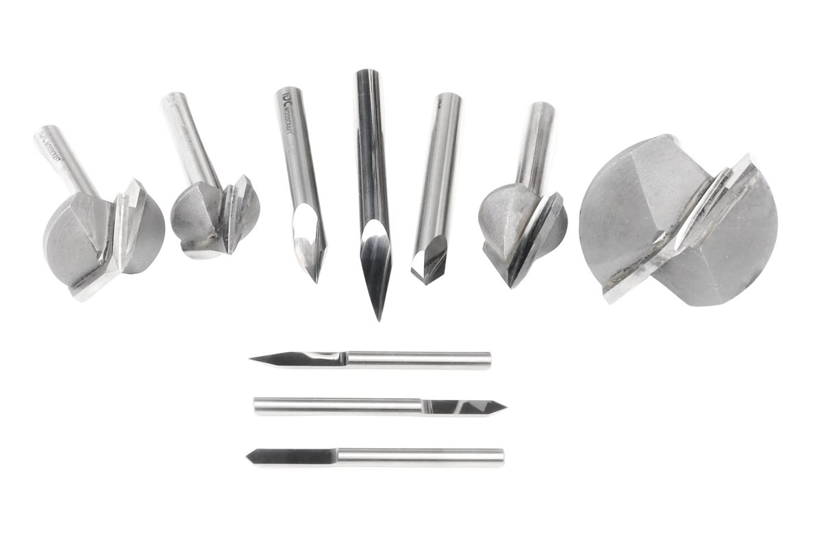 A set of metallic rotary burr drill bits arranged on a plain white background, including several larger angled bits, three smaller straight bits, and one larger circular bit piece.