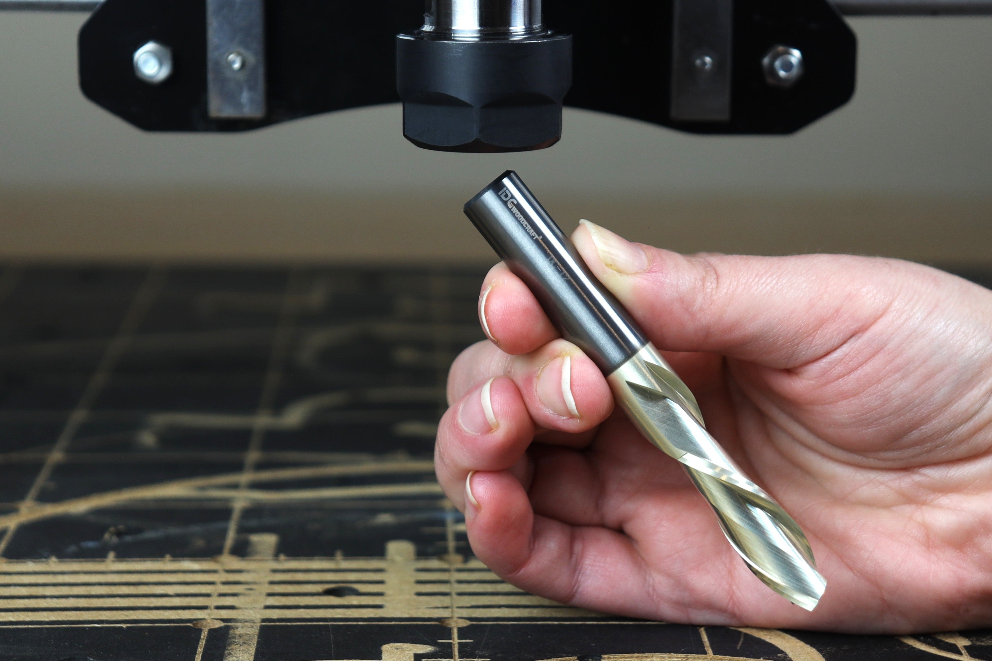 A CNC Router owner holds a large cutting bit on a spillboard